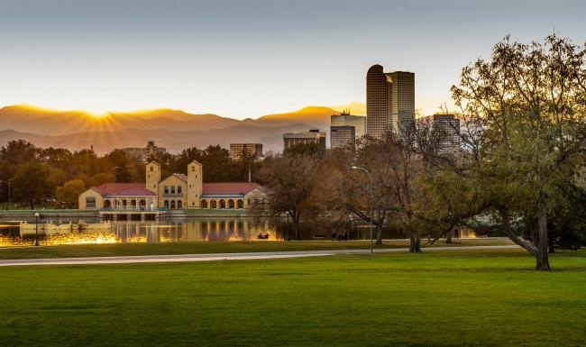 a large green field with trees and buildings in the background